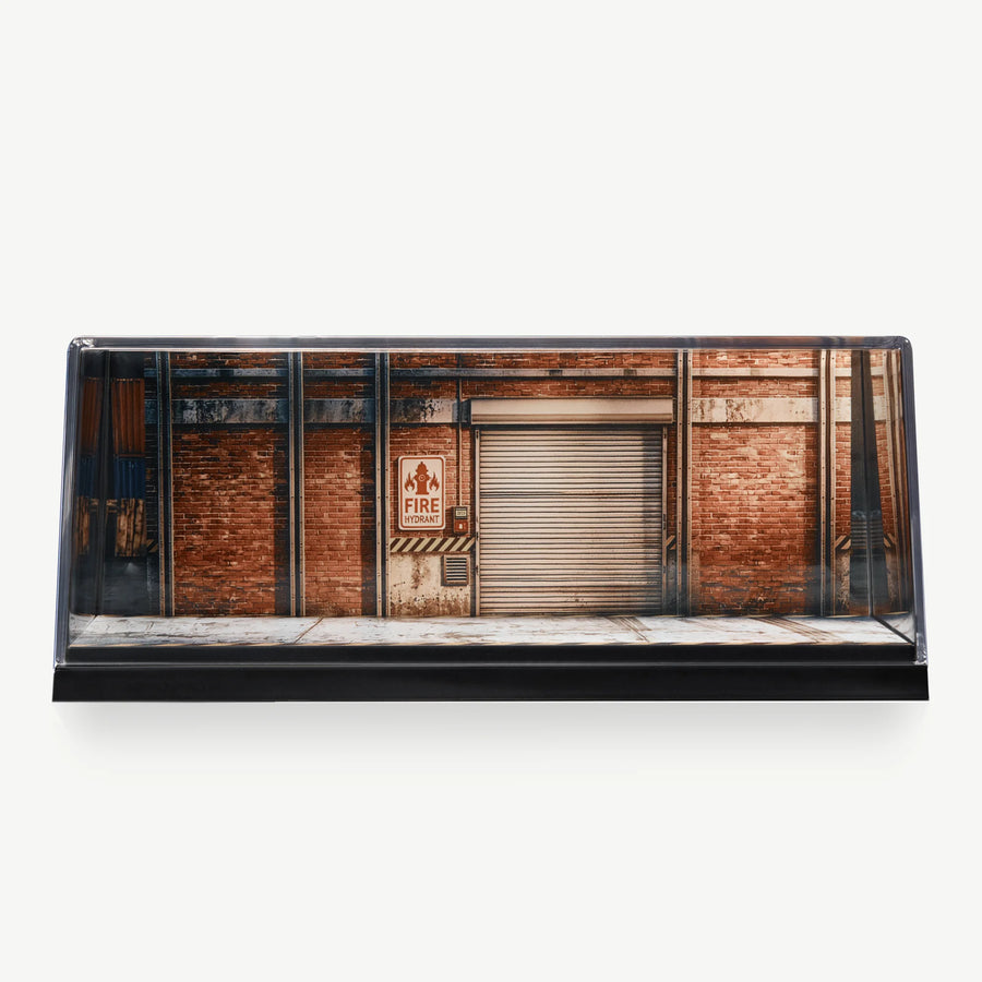 LUXEMARK Clear display case with a red-brick industrial garage backdrop and a metal roller shutter
