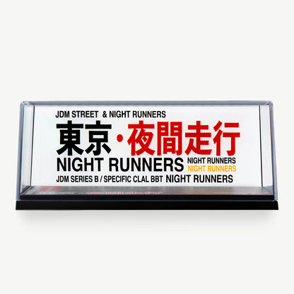 LUXEMARK Clear display case with a white Night Runners backdrop and bold black, red and yellow lettering